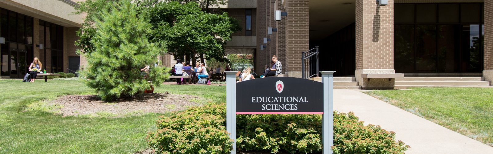 The exterior of the Educational Sciences Building with people eating lunch in the courtyard.